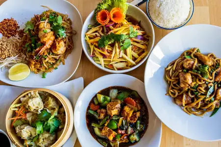 Stół z tajskimi daniami: pad thai, sałatka z mango, curry i pierożki