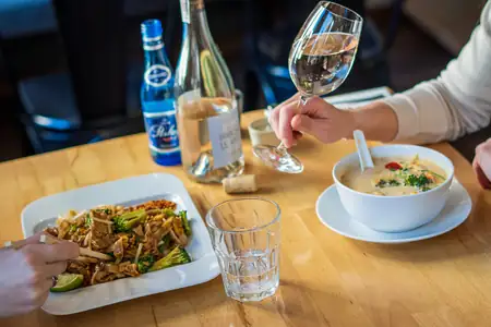 Pad thai, zupa tom kha i wino przy stoliku